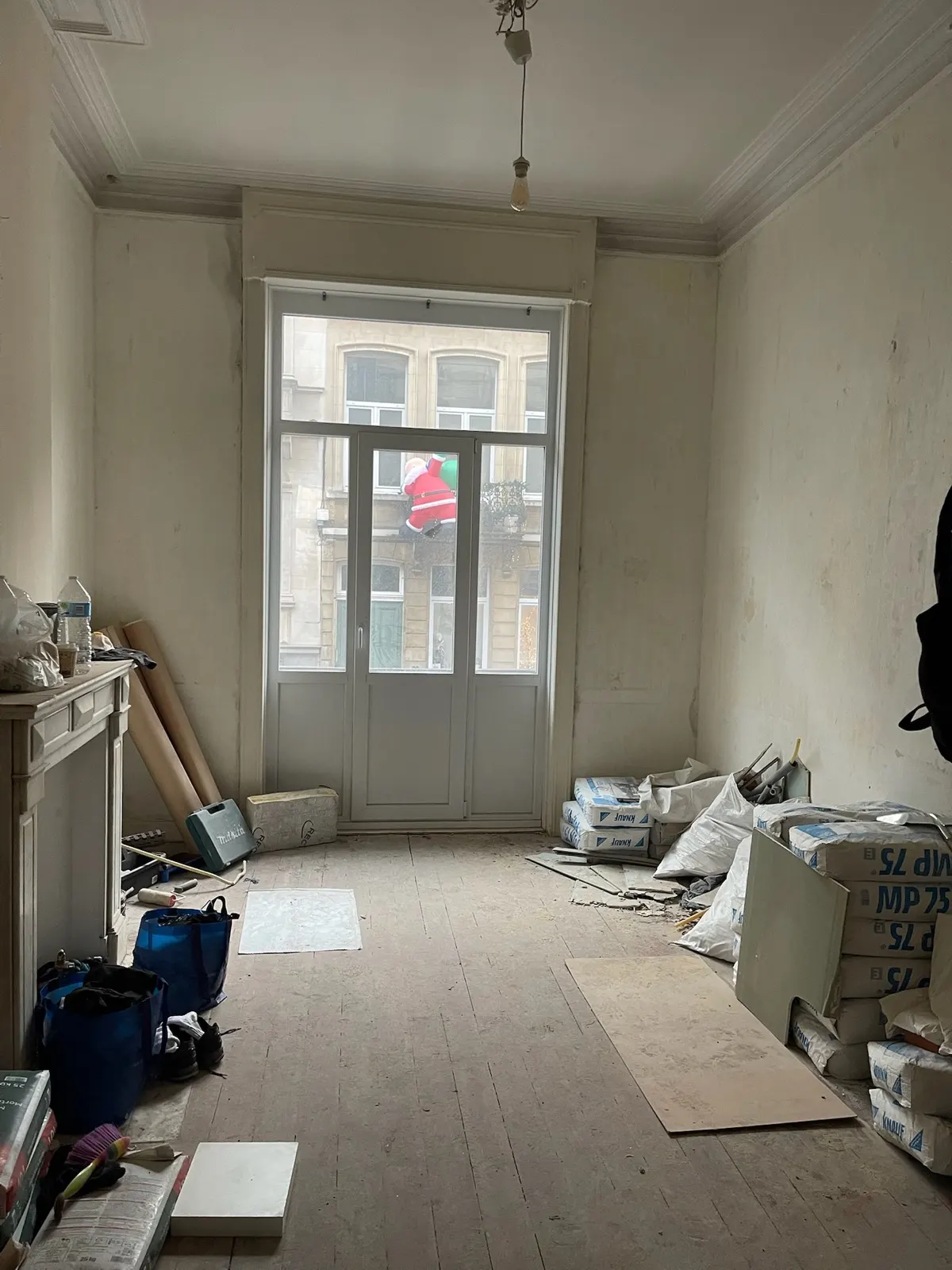 Avant travaux : pièce aux enduits abîmés et plancher nu, matériaux de chantier en attente