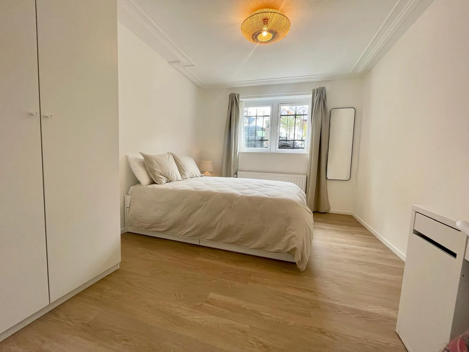 Chambre repeinte en blanc cassé, corniche conservée, fenêtre à petits carreaux et armoire intégrée