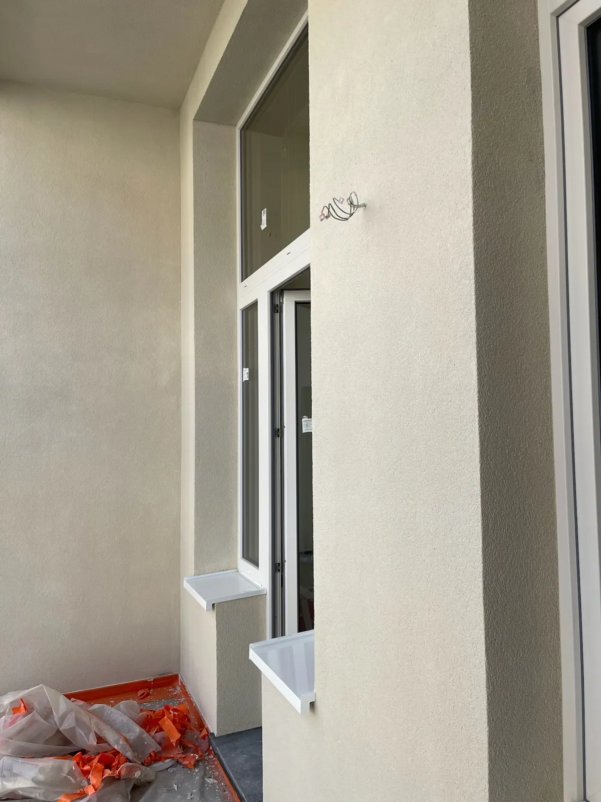 Crépi de façade terminé autour d'une porte-fenêtre, seuils encore protégés