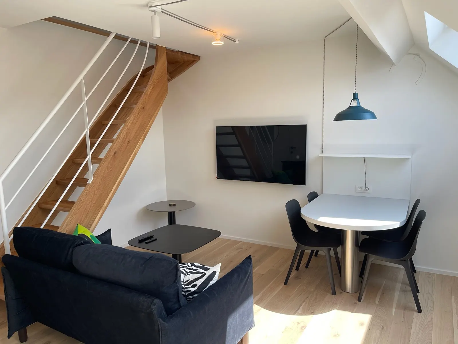Studio sous combles repeint en blanc, escalier bois et garde-corps métallique