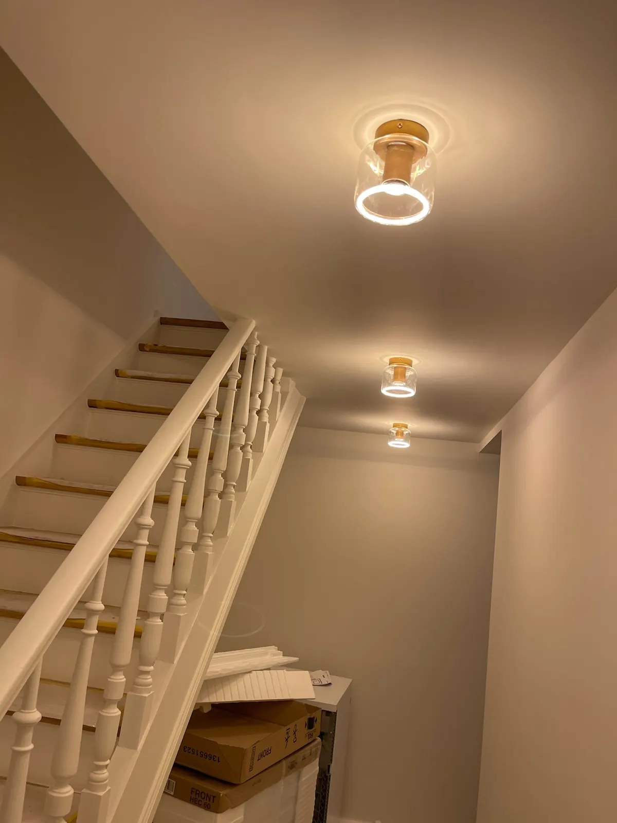 Cage d'escalier aux balustres blancs et main courante en bois, plafond repeint