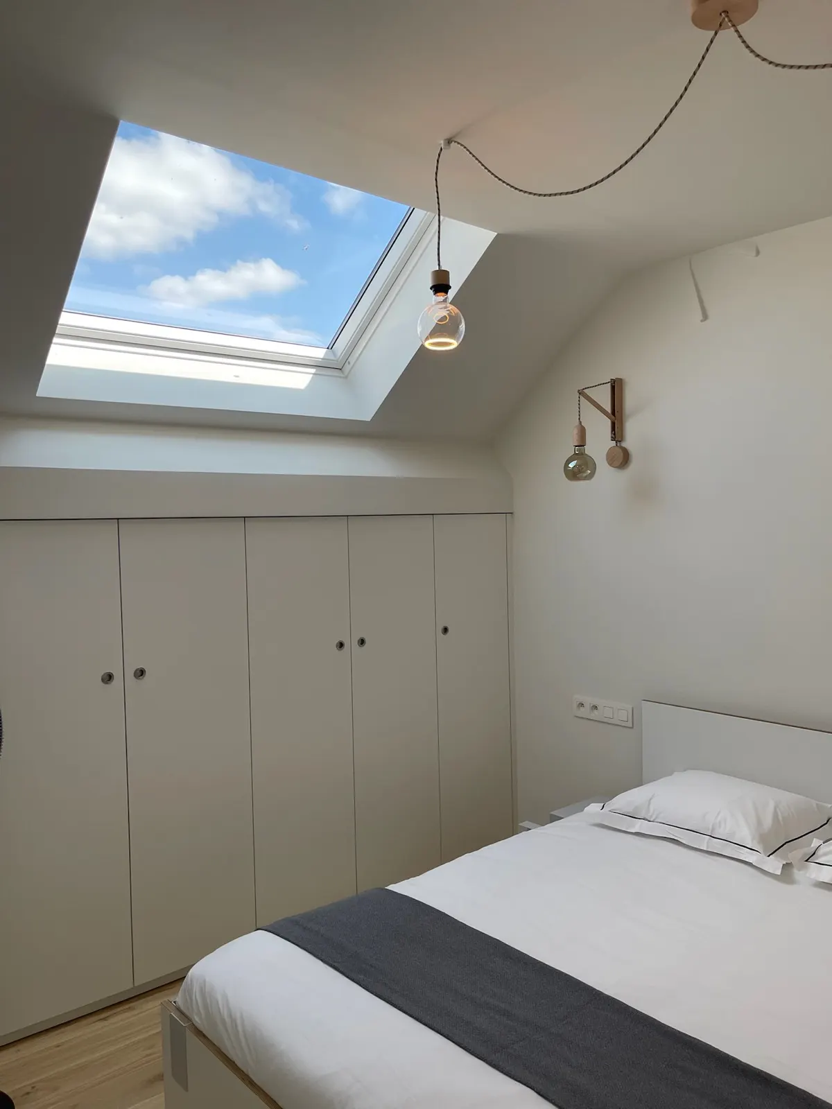 Chambre sous combles, velux ouvert sur le ciel et placards intégrés repeints