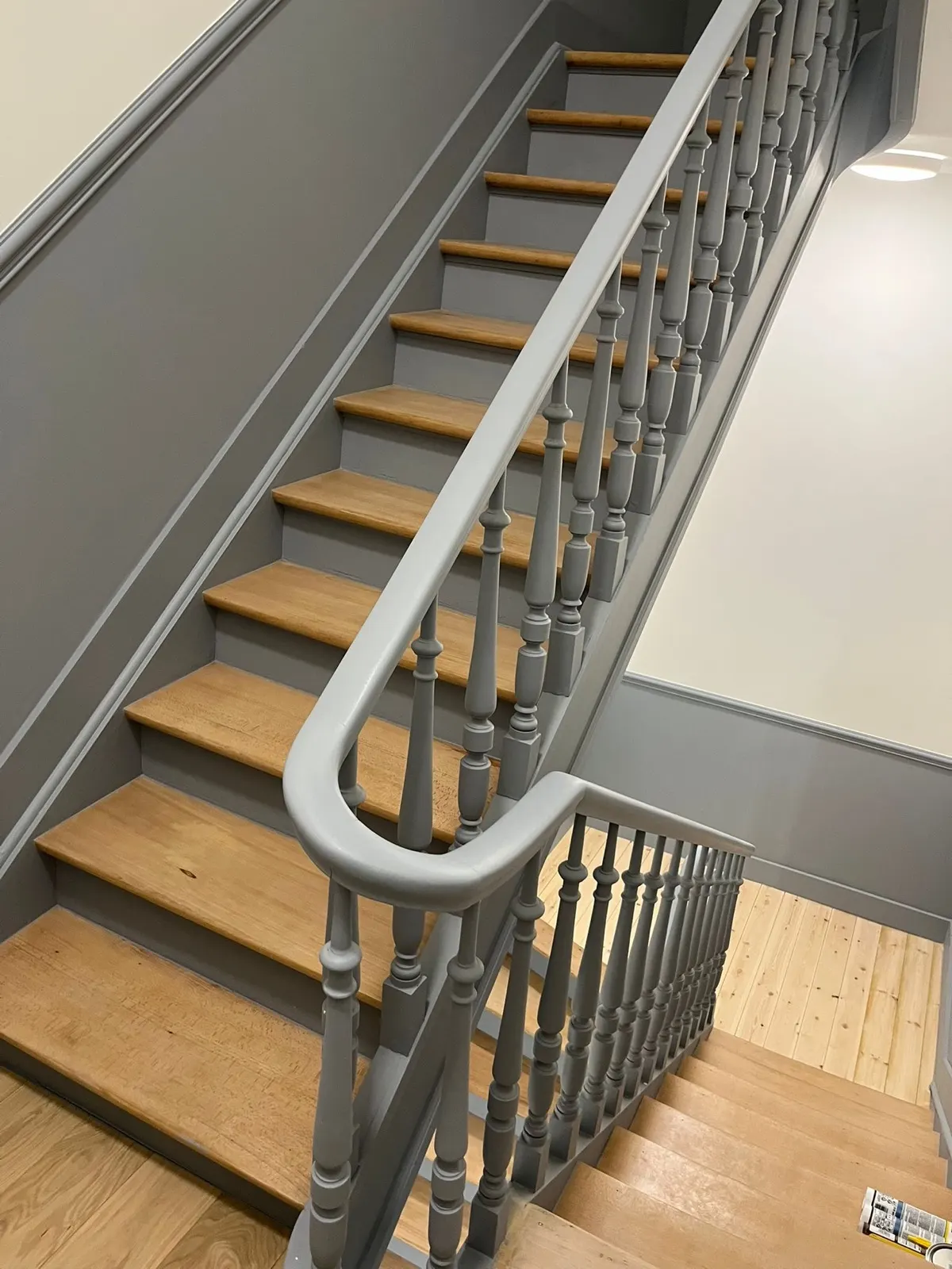 Escalier repeint en gris, balustres tournés et marches en bois clair remises à nu