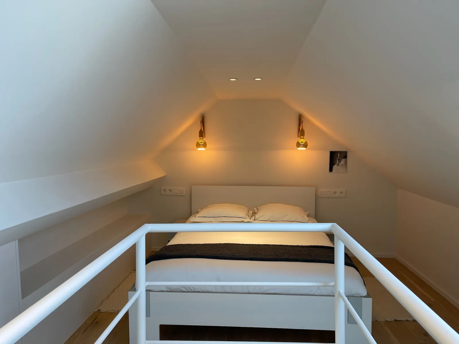 Chambre en mezzanine sous rampants, murs et plafond blancs, éclairage indirect