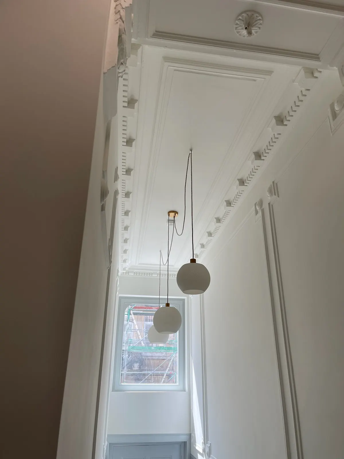 Plafond et corniche à denticules repeints en blanc dans une cage d'escalier bruxelloise