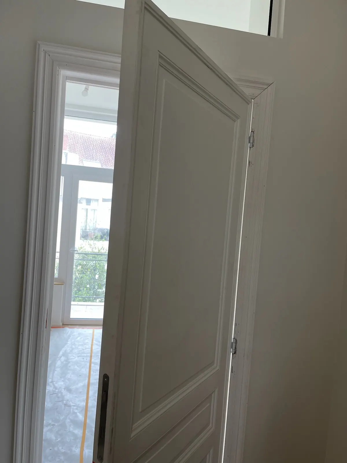 Porte à panneaux d'origine rénovée et laquée, ouverte sur une pièce claire