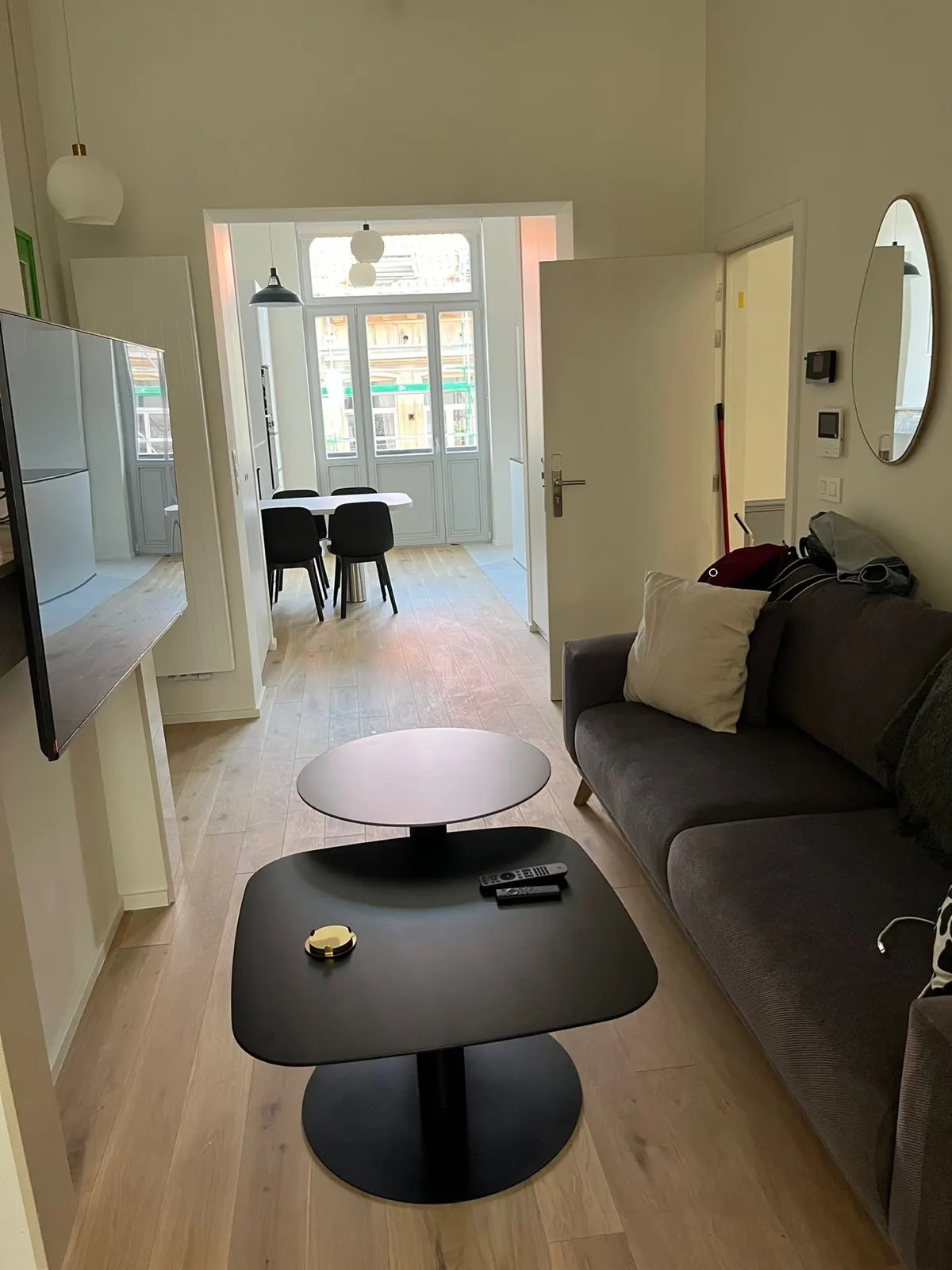Salon d'appartement rénové ouvrant sur la salle à manger et un balcon bruxellois