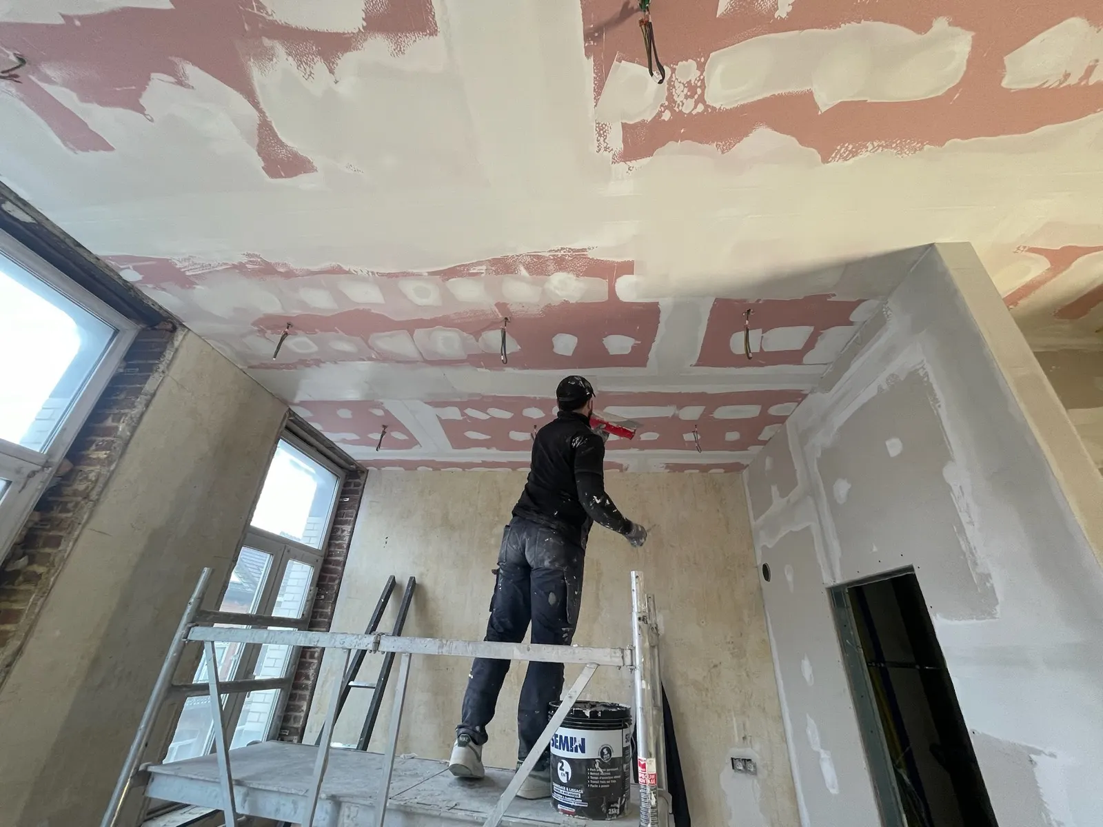 Traitement des bandes d'un plafond en plaques depuis un échafaudage roulant